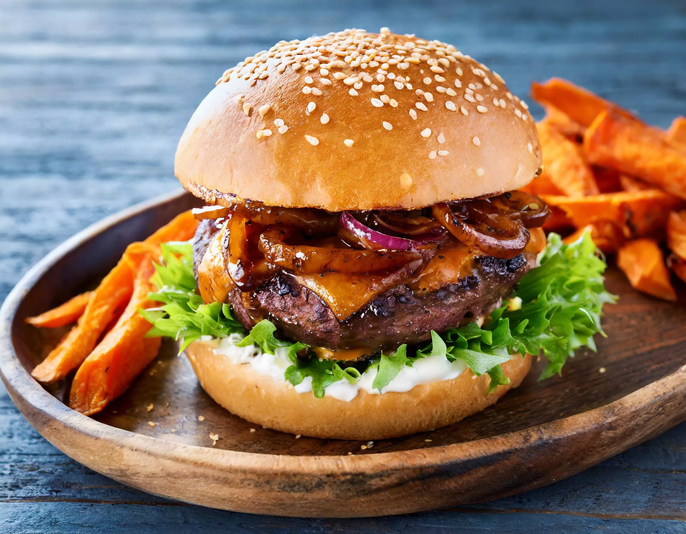 Hamburger mit Salat, Käse, Zwiebeln und Süßkartoffelpommes