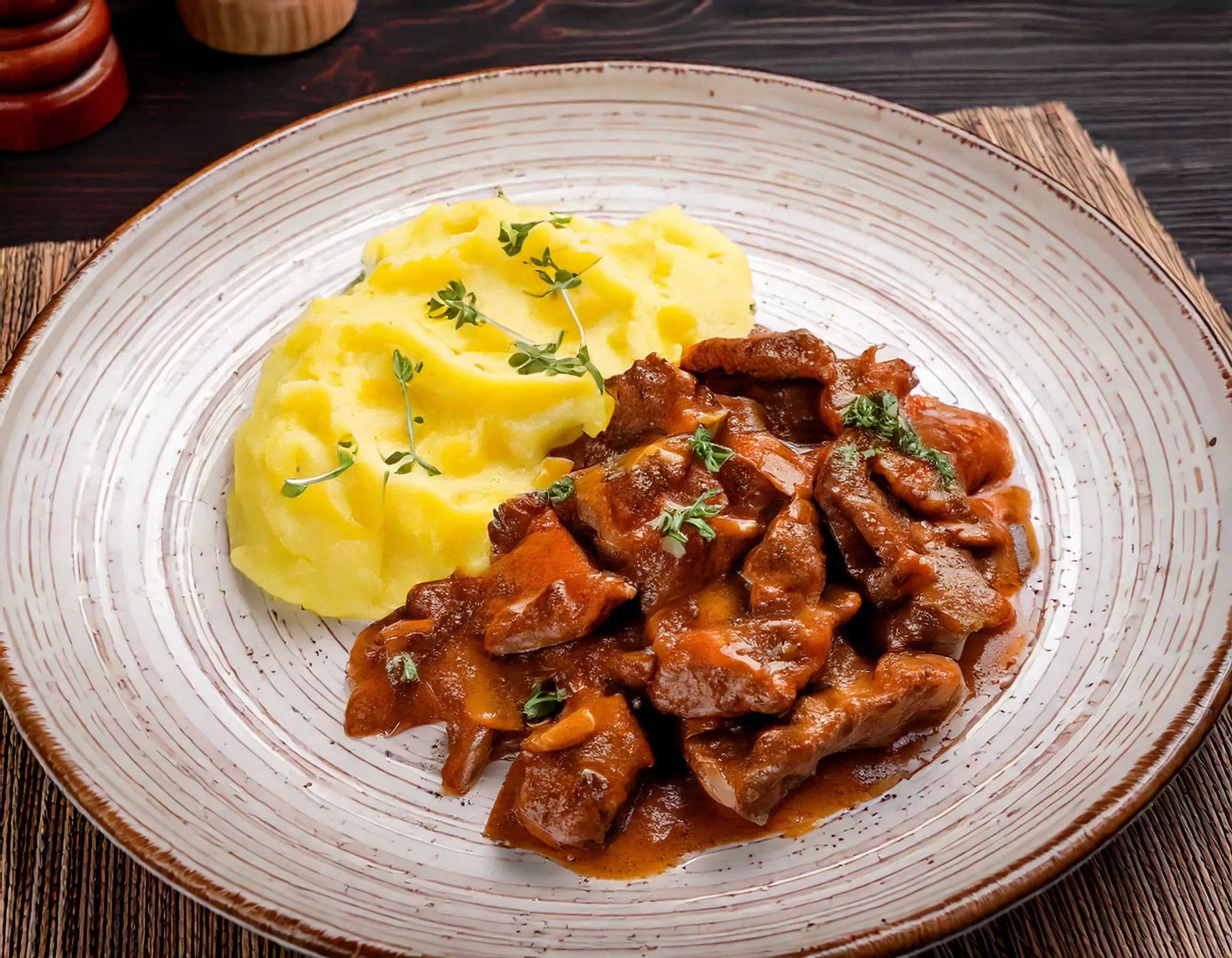 Lebergeschnetzeltes mit Kartoffelpüree und Kräutern auf Teller