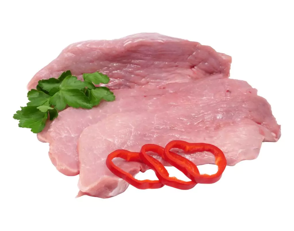 Rohes Schweinefleisch mit Petersilienzweig und drei Scheiben roter Paprika auf weißem Hintergrund.