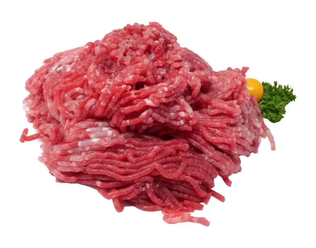 Frisches rohes Hackfleisch mit einem gelben Tomaten und einem Stück Petersilie auf weißem Hintergrund.